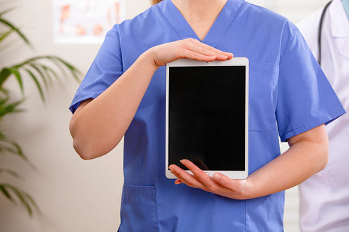 Adult female doctor or nurse showing a digital image or report on a tablet