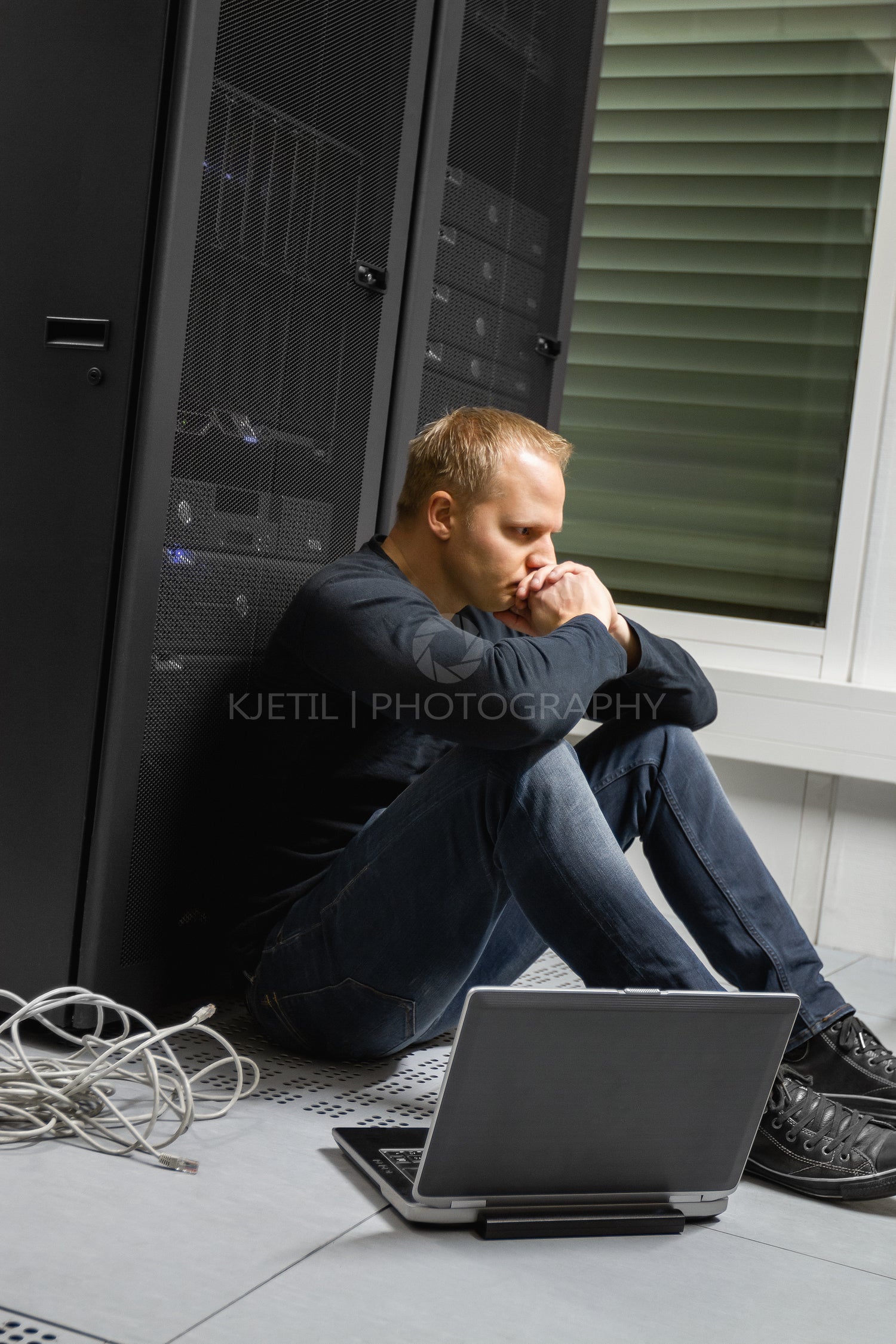 Exhausted Mid Adult IT Consultant Against Servers At Datacenter