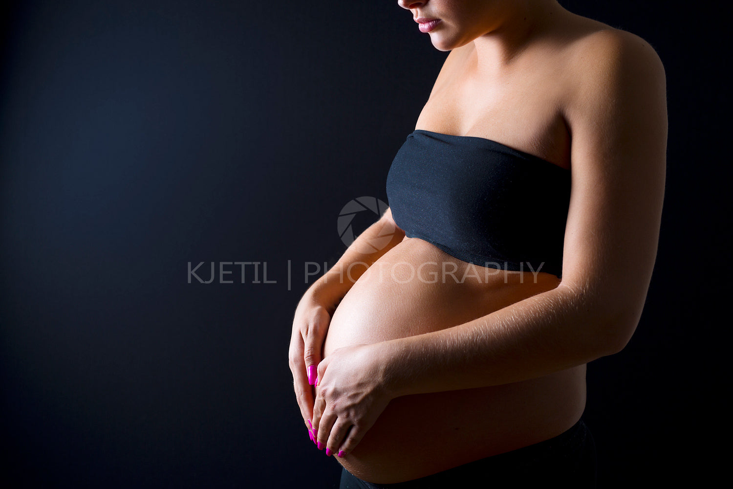 Pregnant woman with her hands on the bare belly