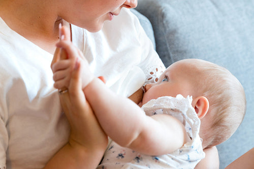 Close-up of caring young mother breastfeeds baby girl