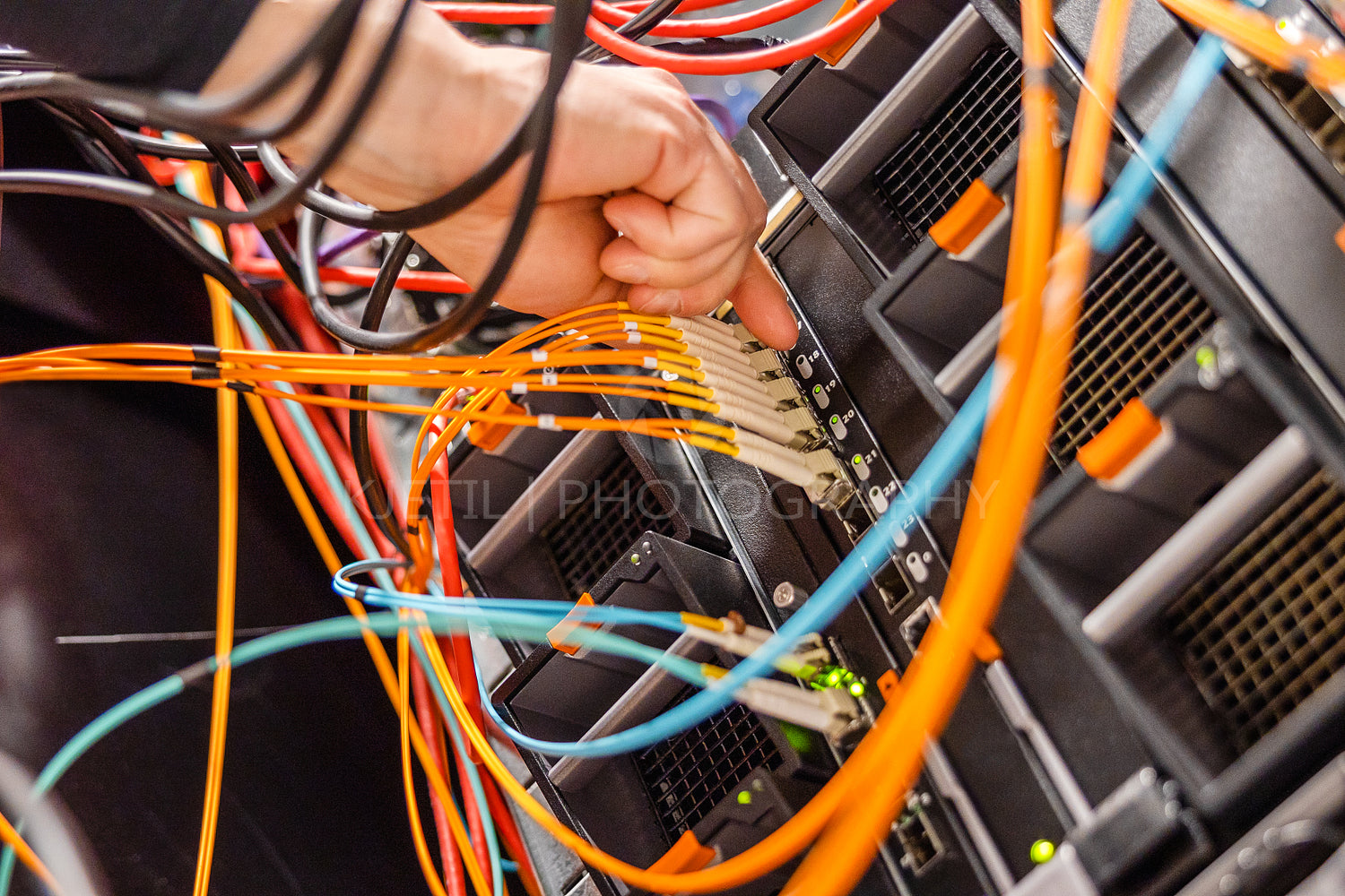 Male IT Engineer Plugging High Speed Fiber Cable In Network Switch