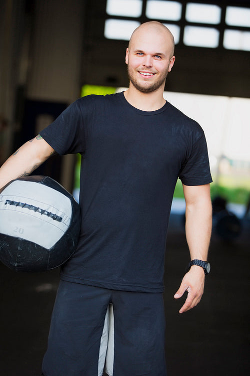 Smiling young man with med-ball at the fitness gym