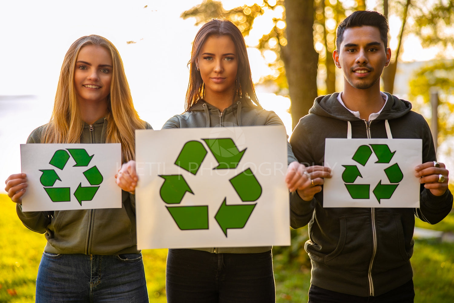 Young environment protective volunteers holding recycling symbol placard
