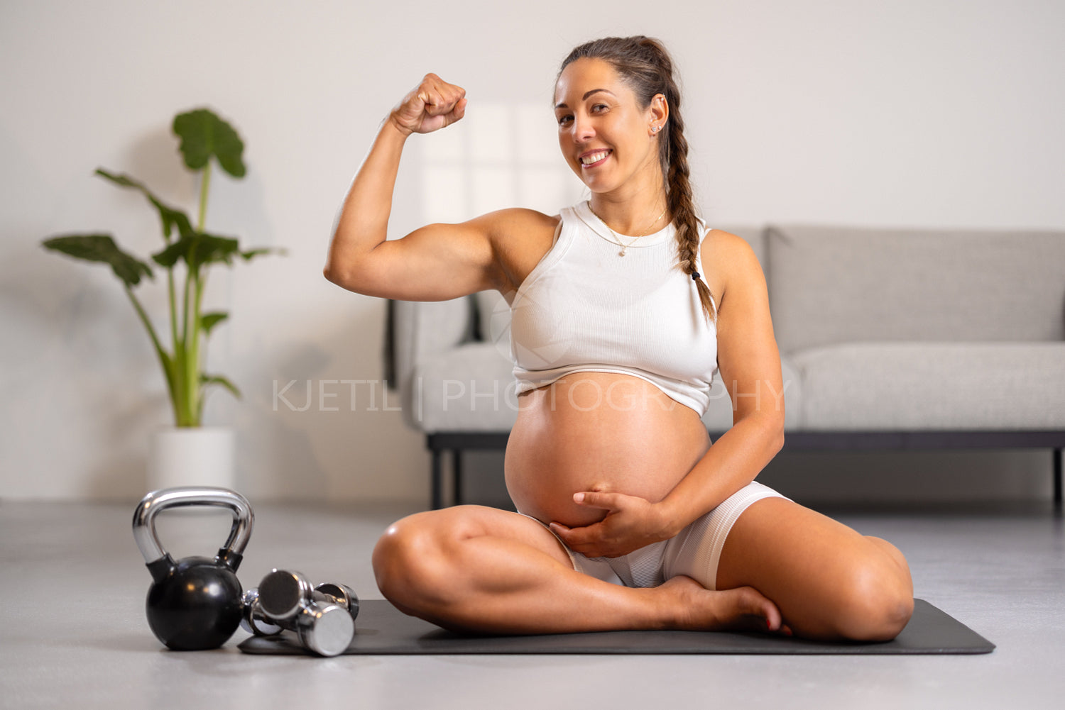 Smiling Strong Pregnant Expecting Mother Showing Off Muscles After Fitness Routine in Living Room