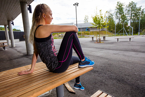 Sporty Young Woman Sitting On Wooden Bench At Park