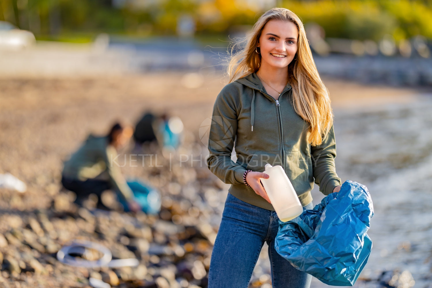 Volunteer holding bottle and garbage bag at beach
