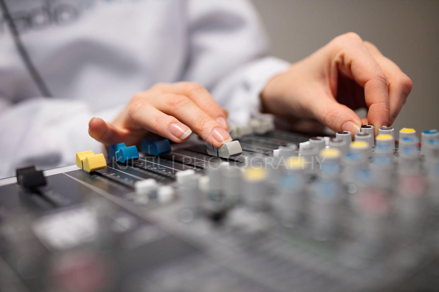 Midsection Of Radio Host's Hands Using Music Mixer In Studio