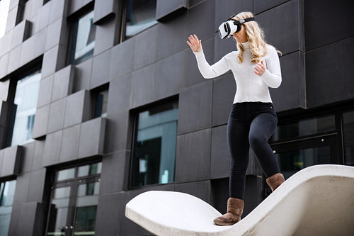 Woman Using Virtual Reality Glasses Technology Against Futuristic Building