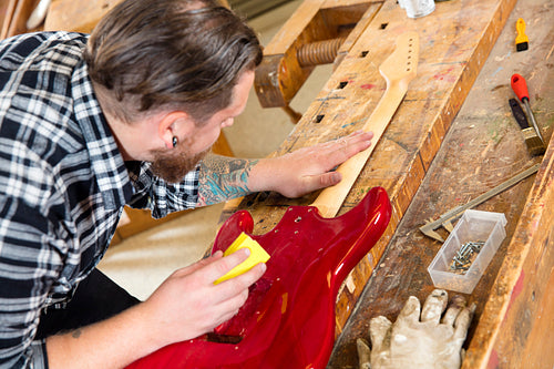 Close-up of craftsman sanding a guitar neck in wood at workshop