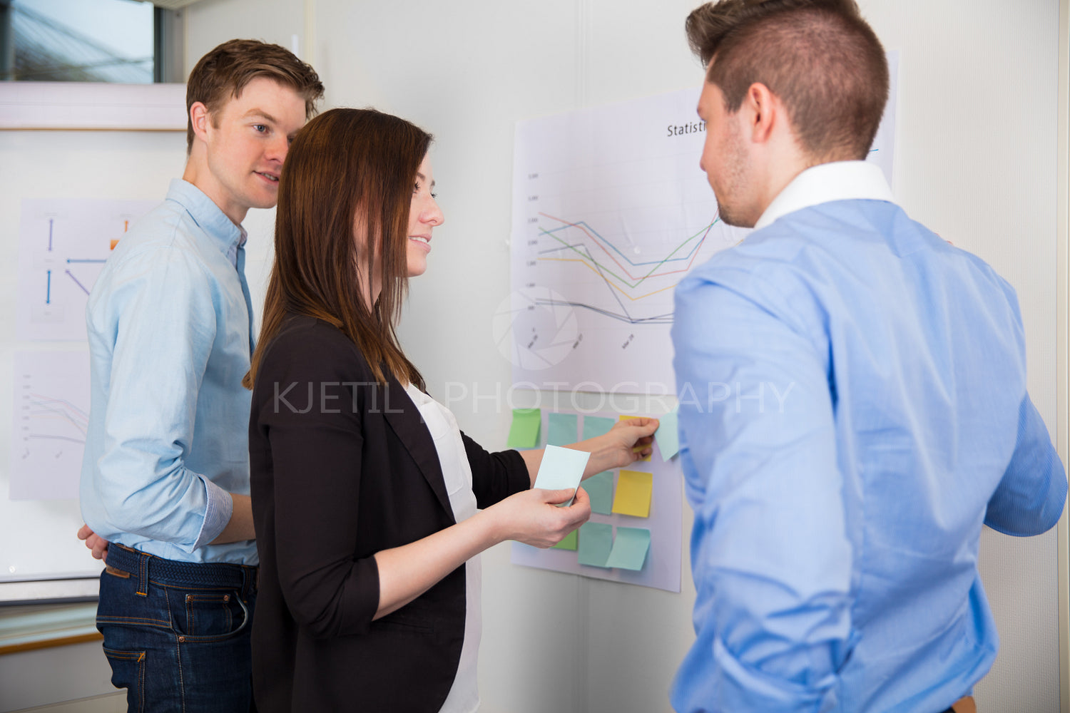 Businesswoman Sticking Adhesive Notes While Standing By Colleagu