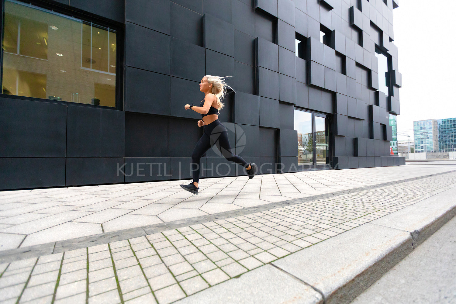 Fast running young woman wearing sports top in modern city environment