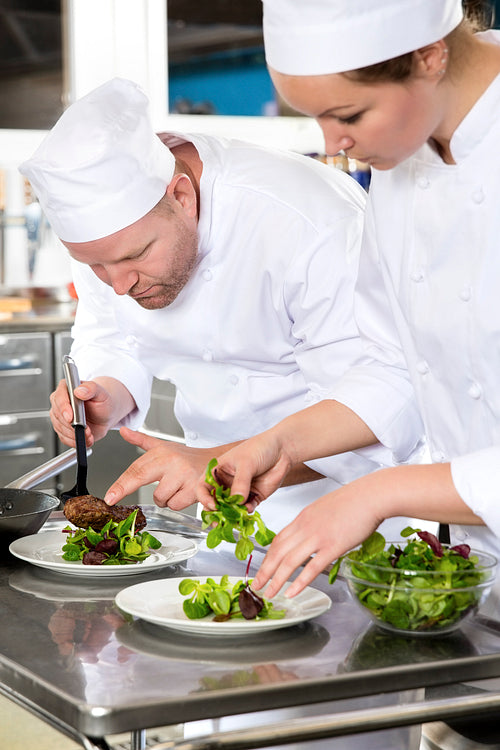Two dedicated chefs prepares steak dish at gourmet restaurant