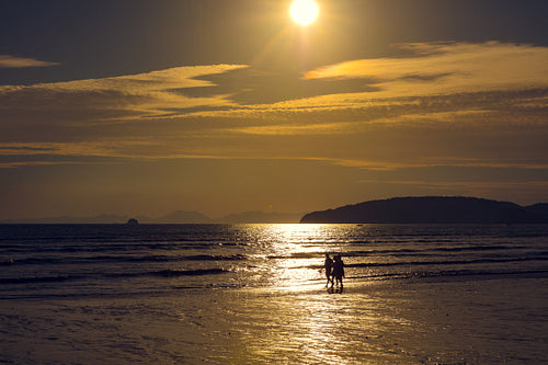 Friends Walking On Shore At Beach During Sunset