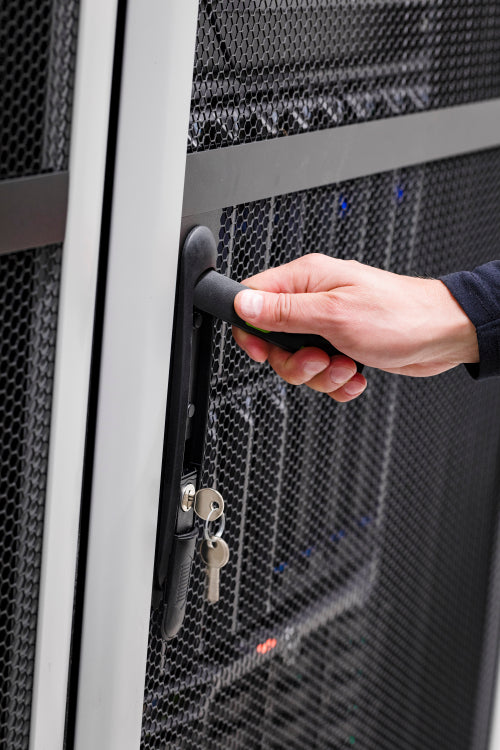 IT engineer opens door to server rack in datacenter
