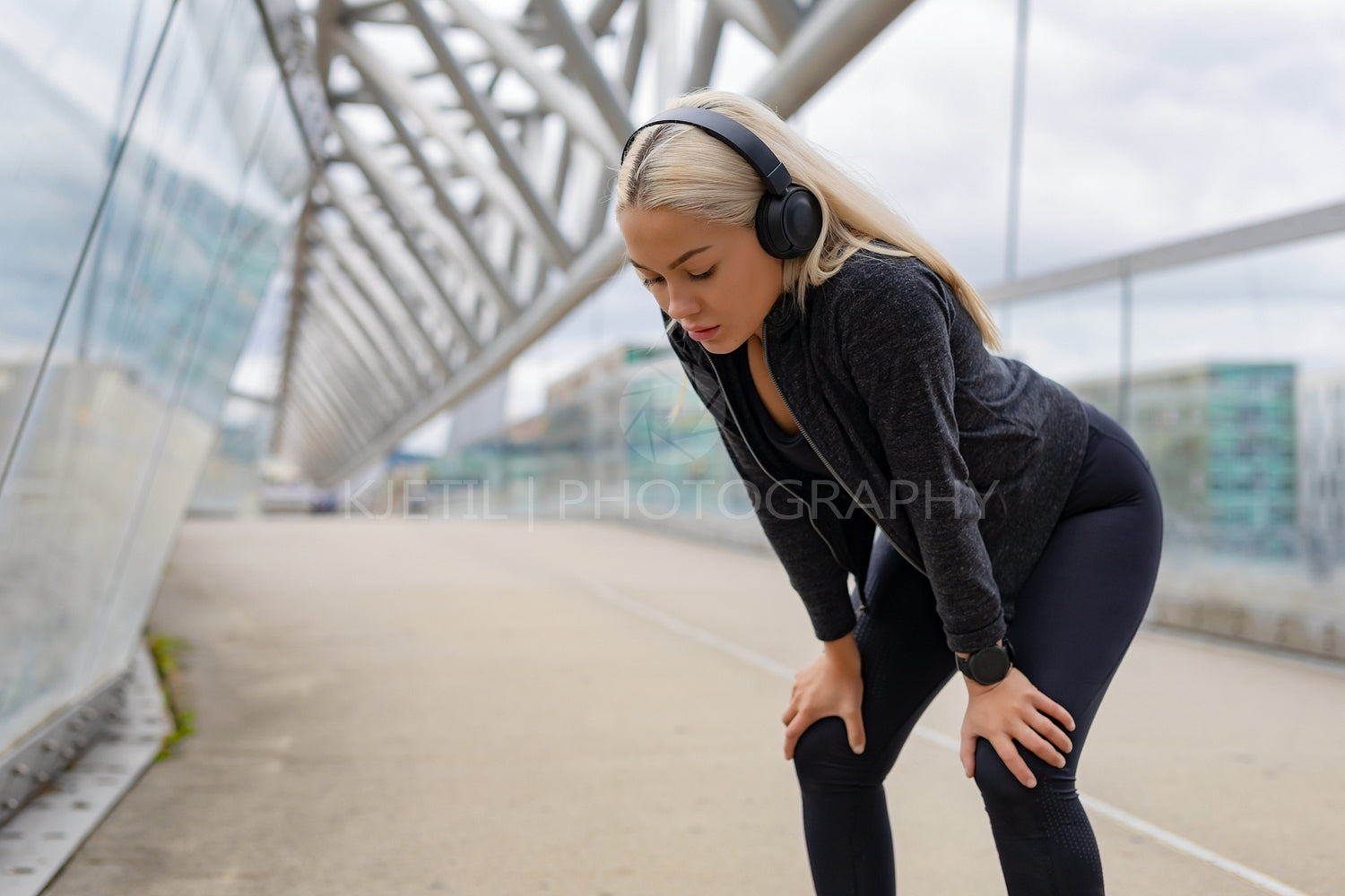 Tired Female Runner Resting With Hands On Knees After Workout