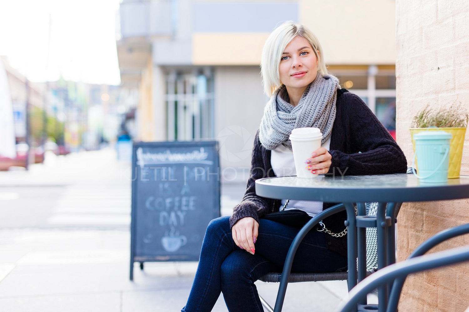 Smiling blonde woman drinking coffee outdoor at cafe