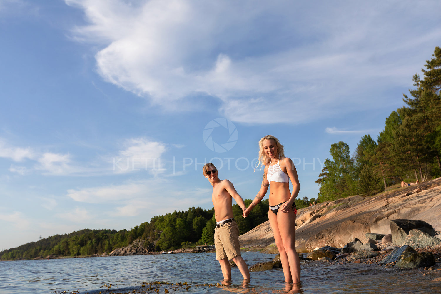 Smiling Young Couple Holding Hands and Standing In Sea