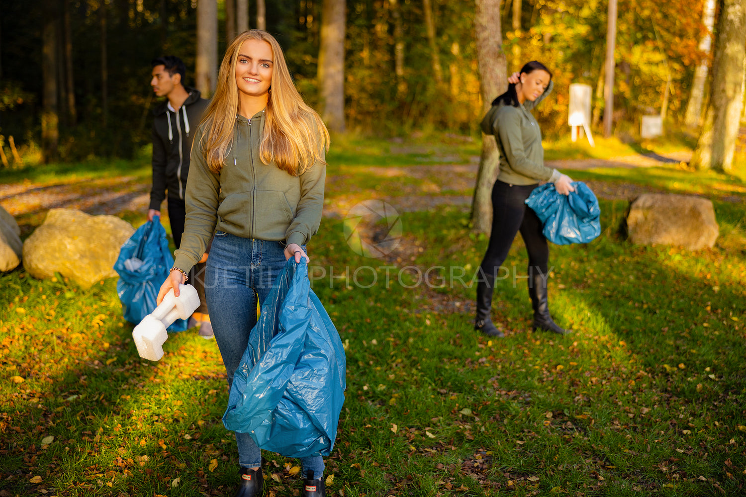 Young female volunteer in a team holding garbage bag at park