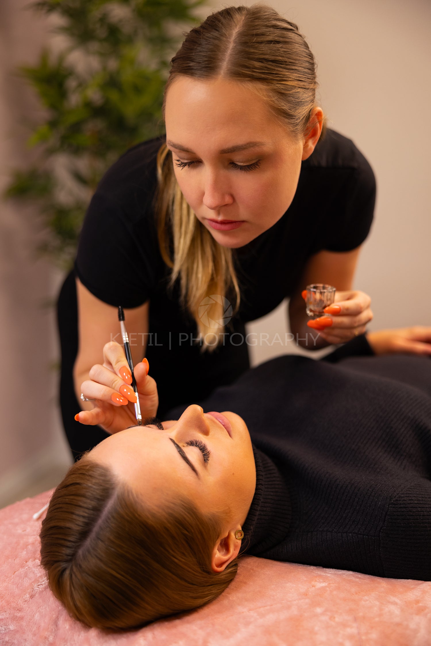 Young Cosmetologist Applying Dye On Female Client's Eyebrow