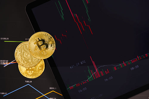 Bitcoin and Tether USDT coins on financial charts on a tablet sceen for crypto currency prices