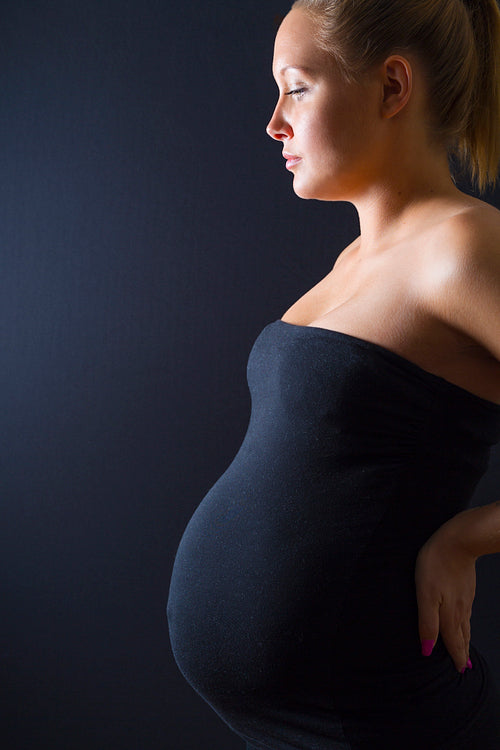 Beautiful pregnant woman stand with hands on the back