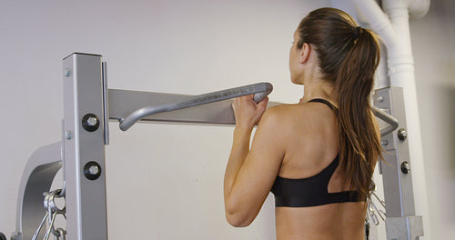 Close-up of active fitness woman doing heavy pull-ups in fitness gym