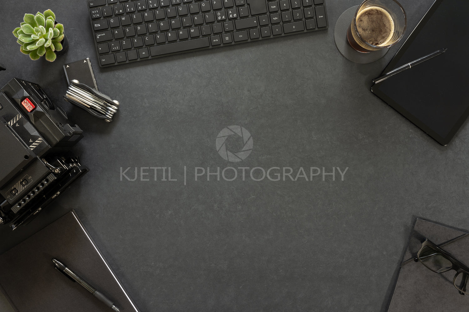 Overhead view of keyboard and diary with photographic equipment on table