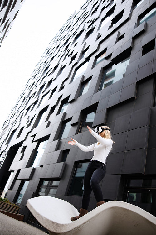 Woman Wearing Virtual Reality Glasses Between Futuristic City Buildings