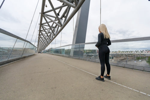 Fitness woman runner rests before running intervall workout on bridge