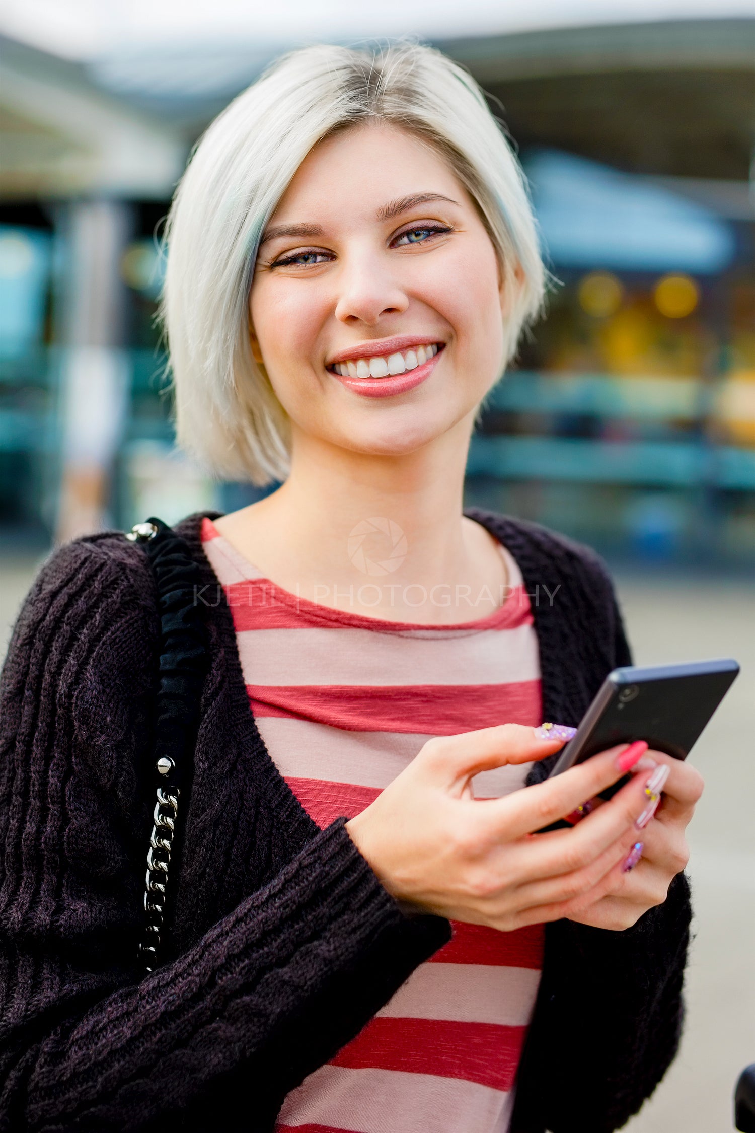 Woman Smiling While Using Smart Phone Outside Train Station