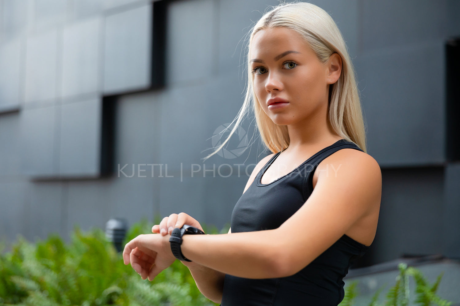 Young blonde woman checking her fitness smart watch device in city