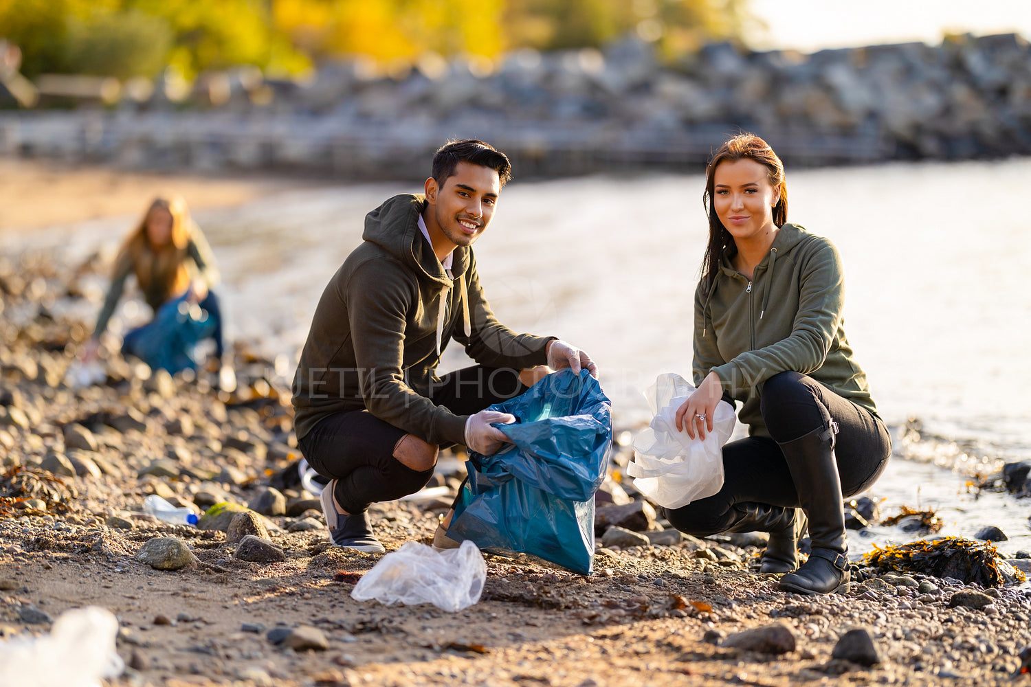 Portrait of smiling young volunteers cleaning beach for plastic