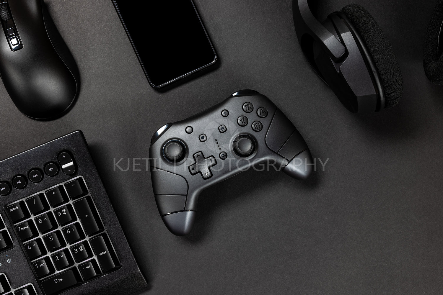 Top view of game controller with gadgets and mobile phone on black gamer desk