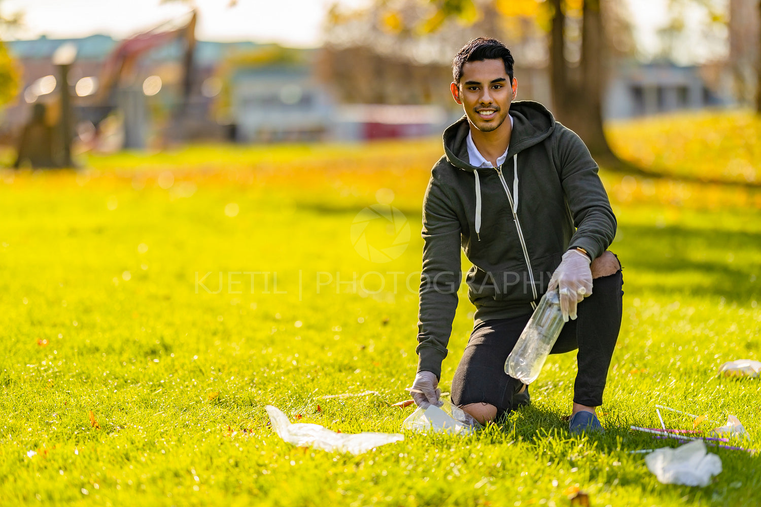 Smiling and committed volunteer cleaning garbage on grass at park