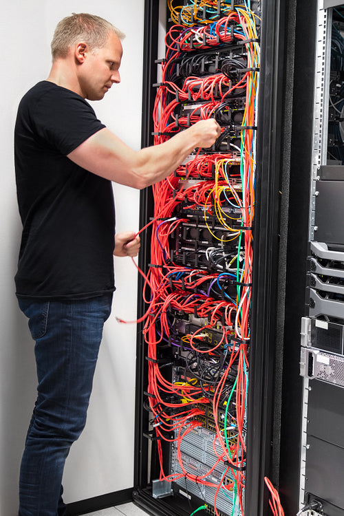 IT Engineer Checking With Network Cables Connected To Servers