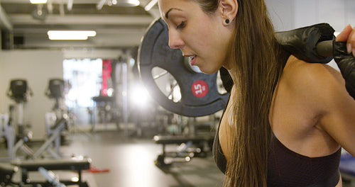 Close-up of a sporty woman training squat with heavy weights in fitness gym