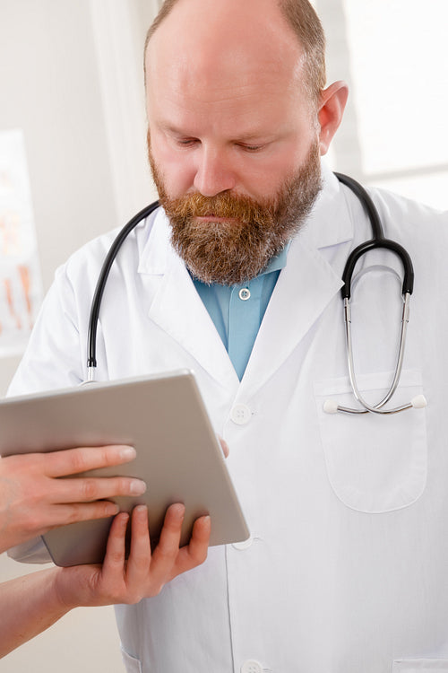 Doctors discussing report about a patient at tablet computer in hospital