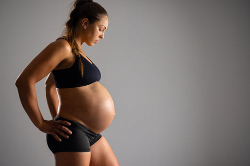Pregnant woman with bare belly and hands on her hips