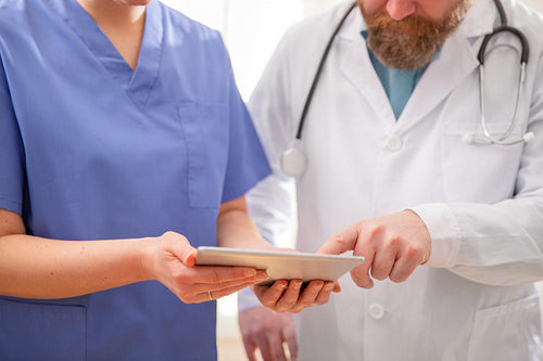 Doctor and nurse discussing patients tests at tablet computer in hospital