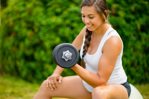 Expectant Female Exercising With Dumbbells To Strengthen Arms In