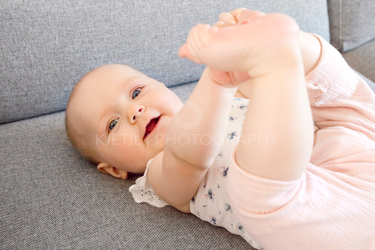 Smiling baby girl with blue eyes playing on the sofa