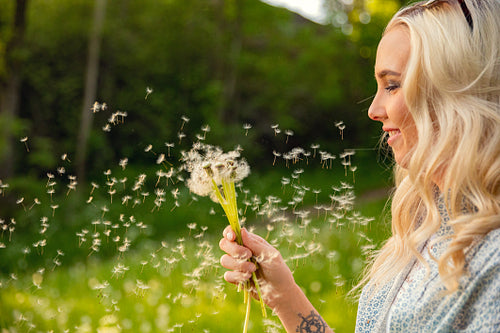 Closeup Of Young Woman Looking At Flying Dandelion Seeds