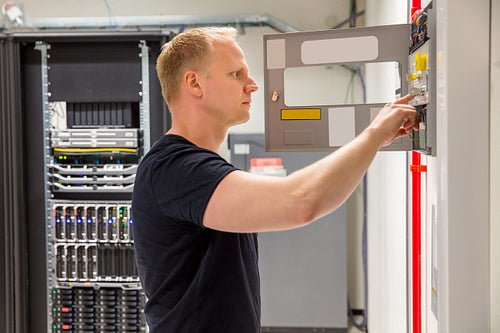Confident Male Technician Checking Fire Panel In Datacenter