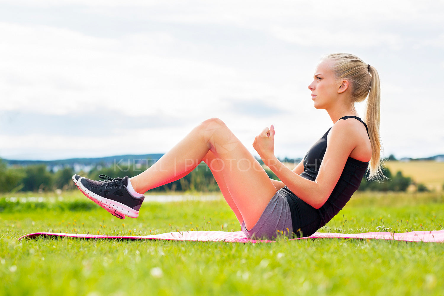 Young woman doing sit ups in the park