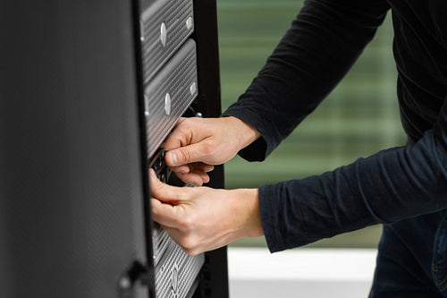 Male Technician Adjusting Disk Cabinet In SAN At Datacenter