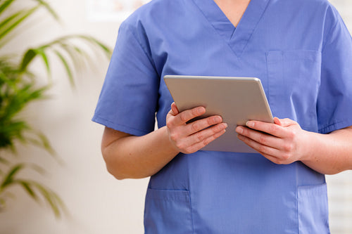 Adult female doctor or nurse looking at a digital image or report on a tablet
