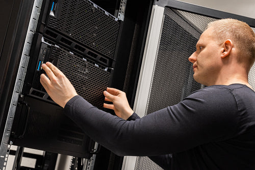 Focused Male Technician Working With Servers In Datacenter
