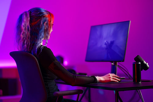 Focused professional e-sport gamer girl streaming and plays first-person shooter online video game on PC