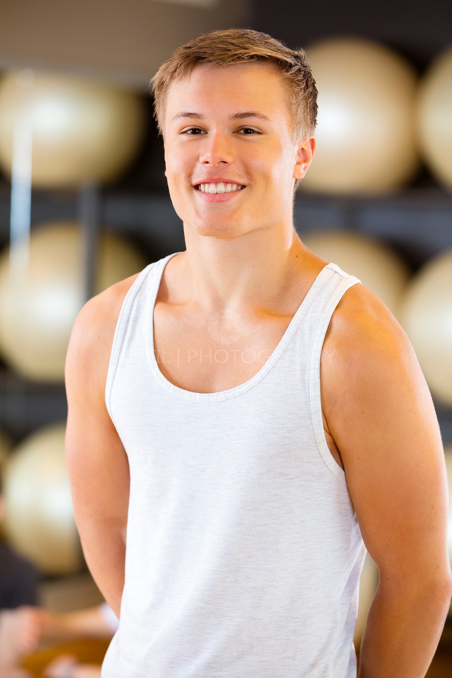 Smiling young man in workout outfit at fitness gym