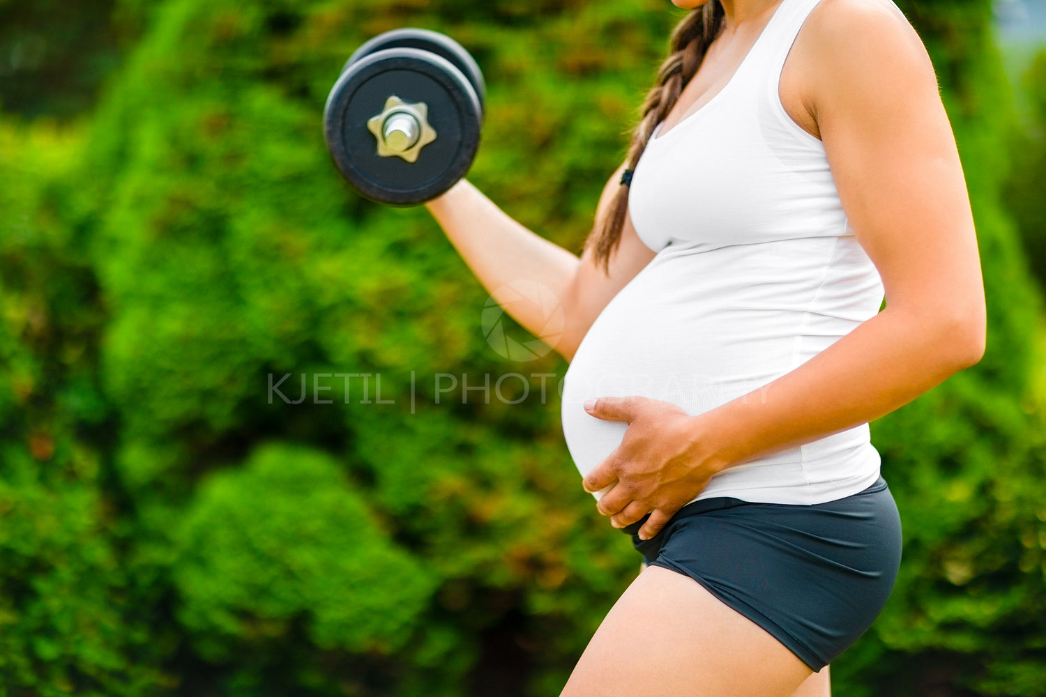 Pregnant Woman Touching Stomach While Exercising With Dumbbell